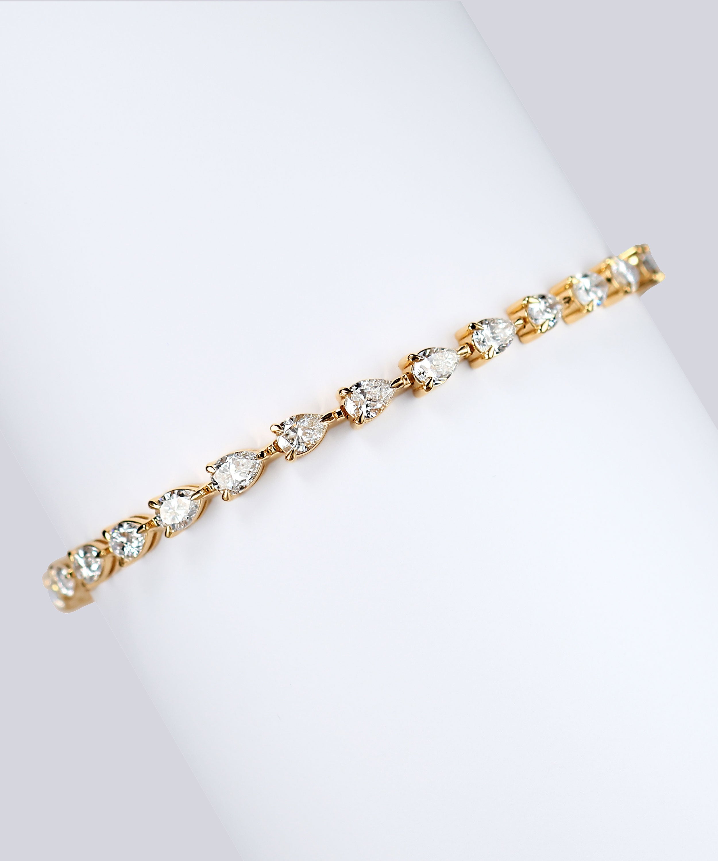 7ct lab grown pear diamond tennis bracelet in 18k gold wrapped around white card