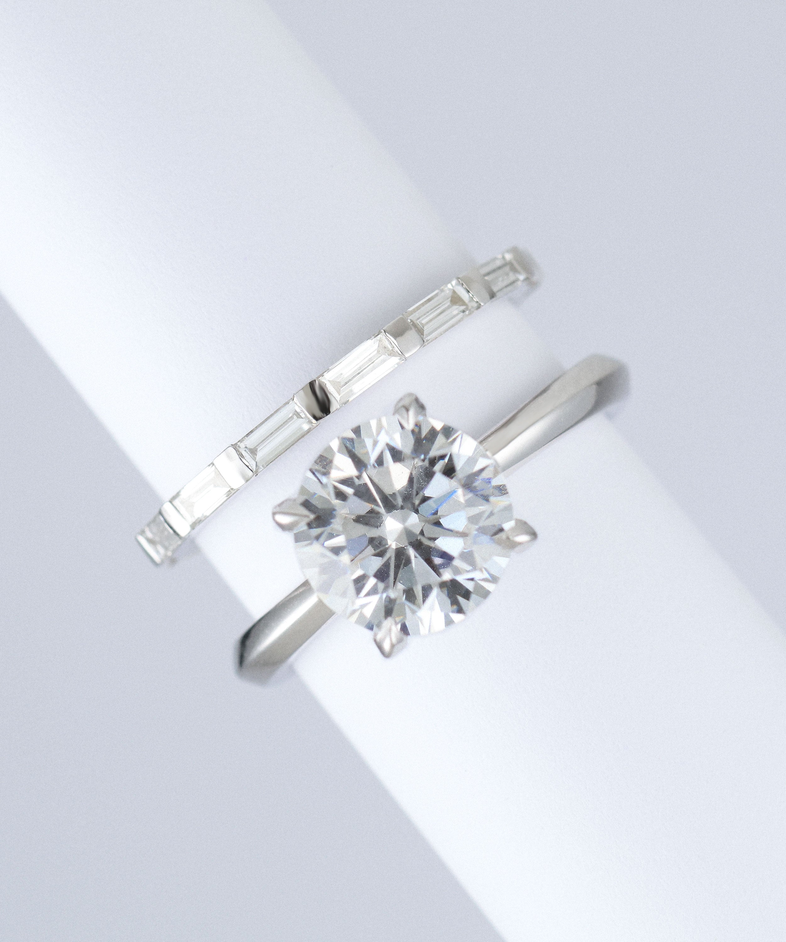 skinny baguette wedding band in platinum. made with lab grown diamonds and recycled precious metals. sat next to round engagement ring
