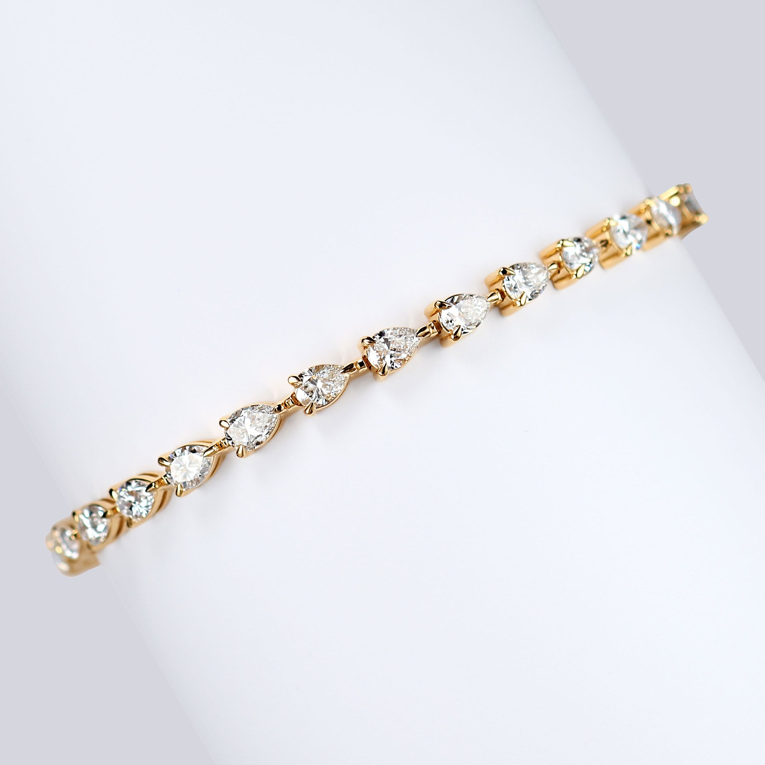 7ct lab grown pear diamond tennis bracelet in 18k gold wrapped around white card 