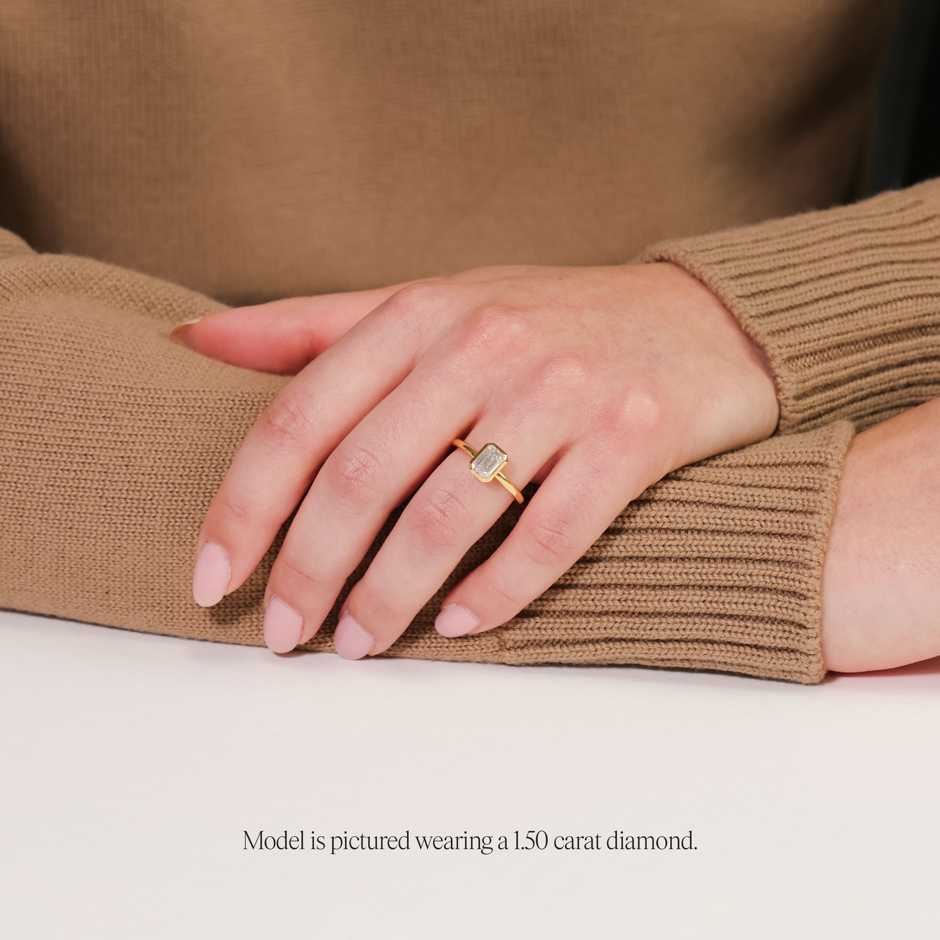 model wearing a 1.5 carat bezel set emerald cut solitaire in rubover setting yellow gold