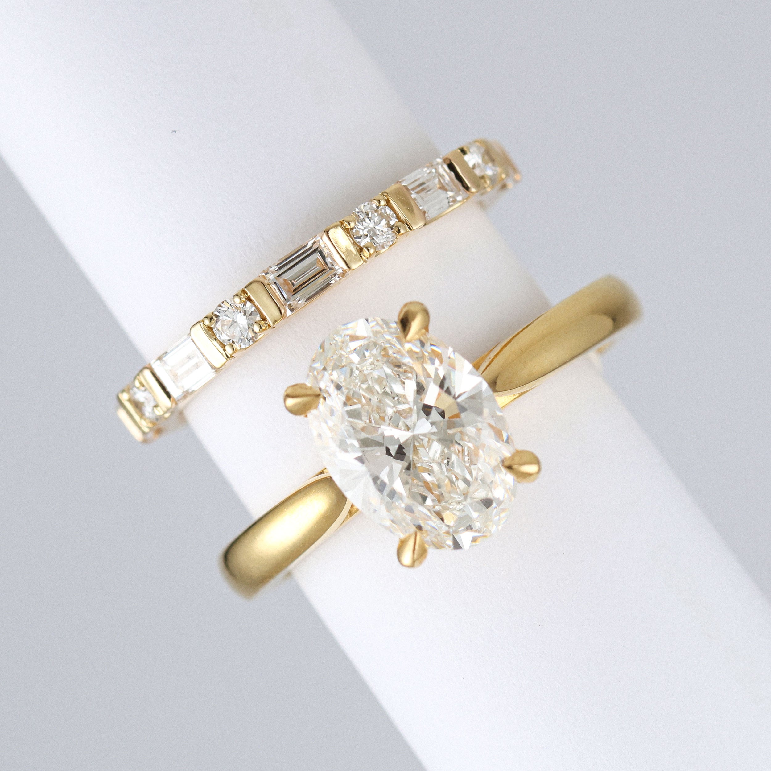 yellow gold round and baguette wedding ring made out of lab grown diamonds and recycled precious metals. Next to an oval engagement ring