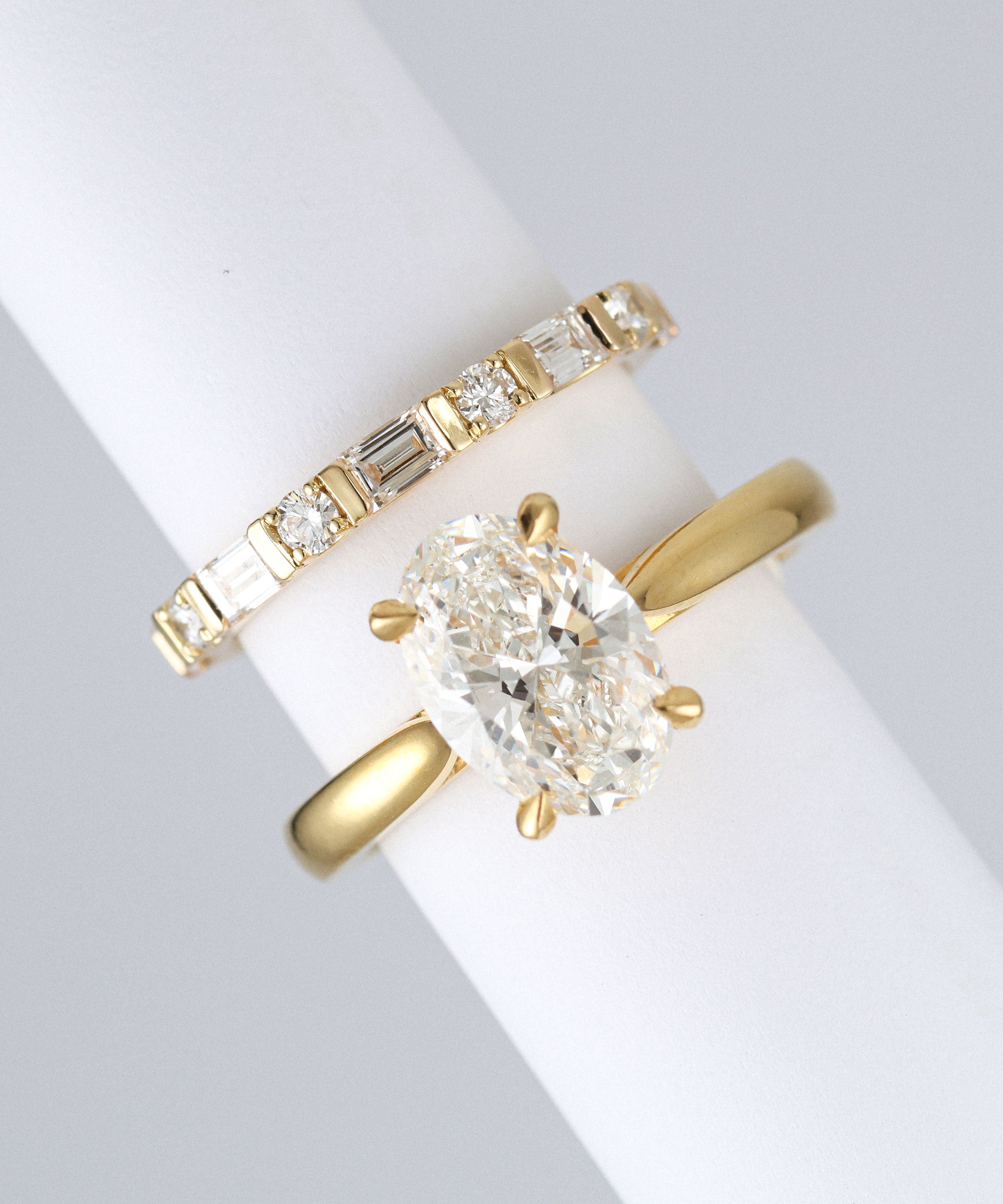 yellow gold round and baguette wedding ring made out of lab grown diamonds and recycled precious metals. Next to an oval engagement ring